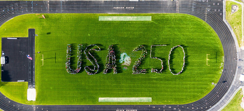 The students and staff of Van Buren Schools spell out USA 250 on the football field.