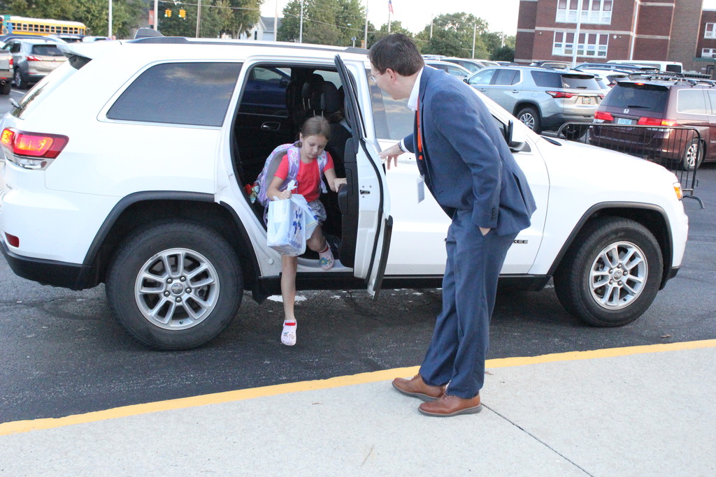 A picture showing Superintendent Dr. Jason Inkrott helping a student out of her car in the morning.