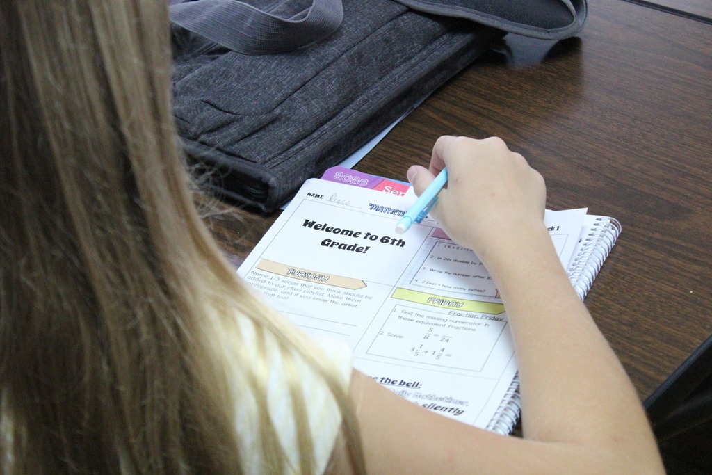 A picture of a student reviewing her weekly sixth-grade math assignments.