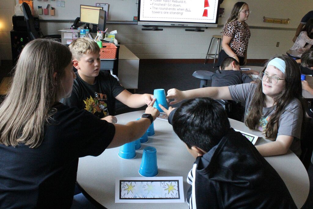 A picture showing Mrs. Spridgeon and three of her students working together to stack cups.