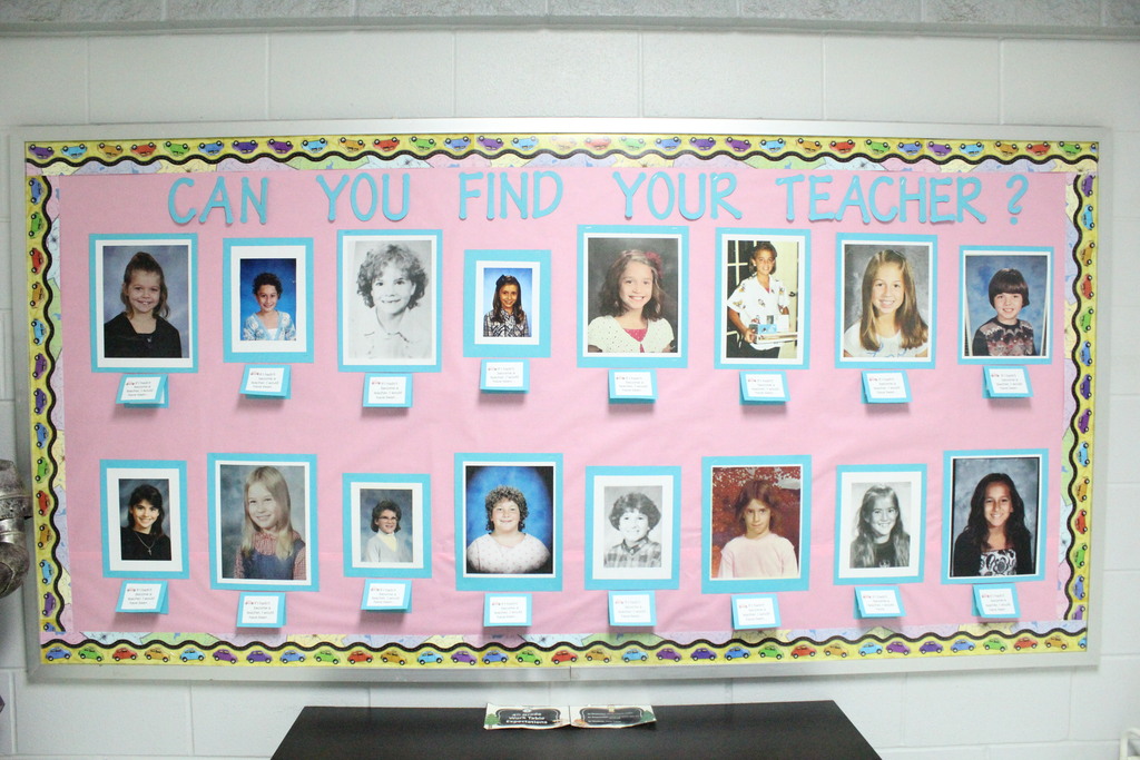 A picture of a bulletin board in the elementary showing pictures of the teachers from when they were in school. 