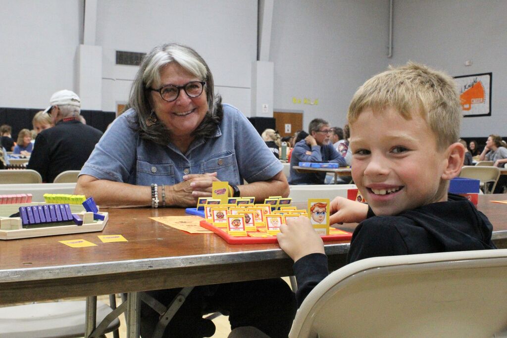 A picture showing a student and a VIP playing the game "Guess Who."