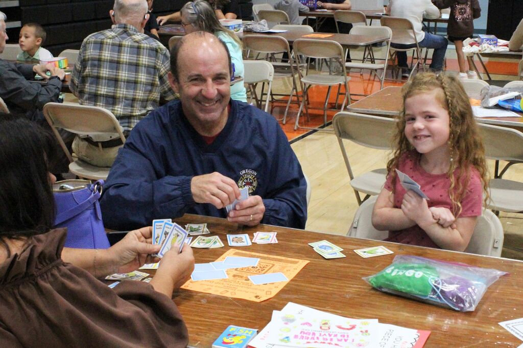 A picture of a student and her two VIPs playing a card game.