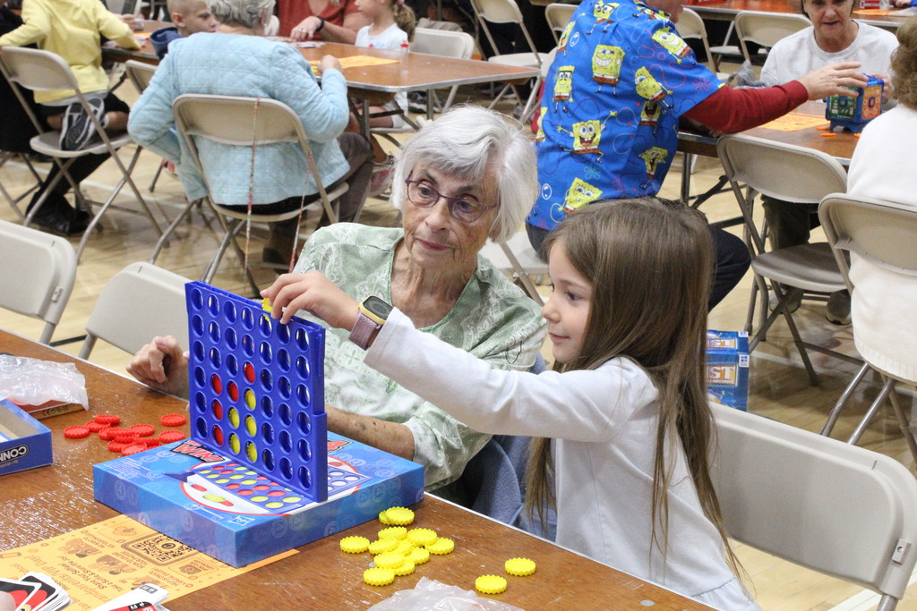A picture showing a student and a VIP playing Connect Four.