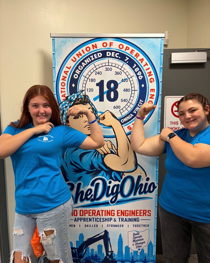 A picture of two students posing in front of a SheDig Ohio sign.