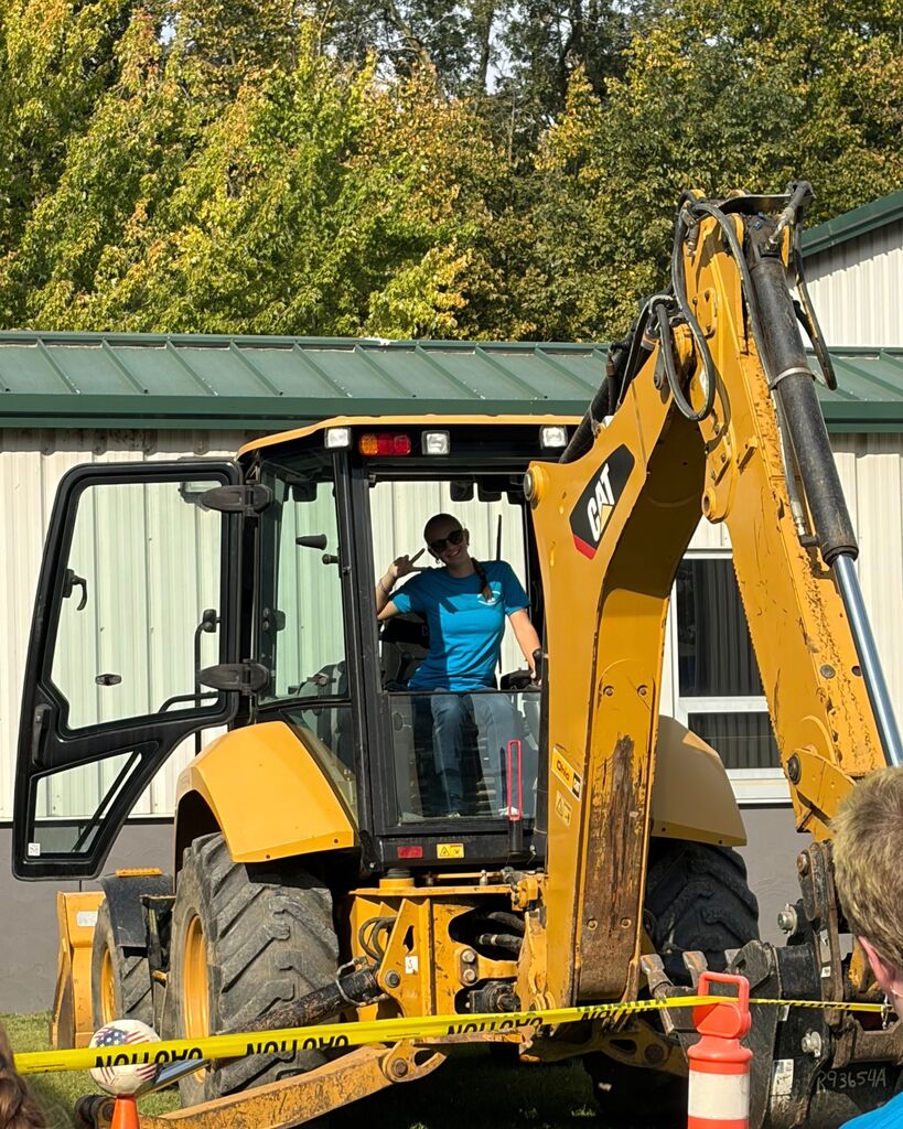 A picture of a student maneuvering a backhoe.