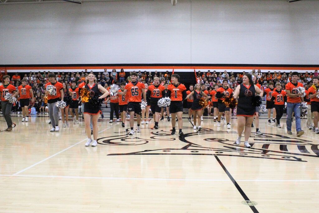 A picture of the football team performing with the cheerleaders.
