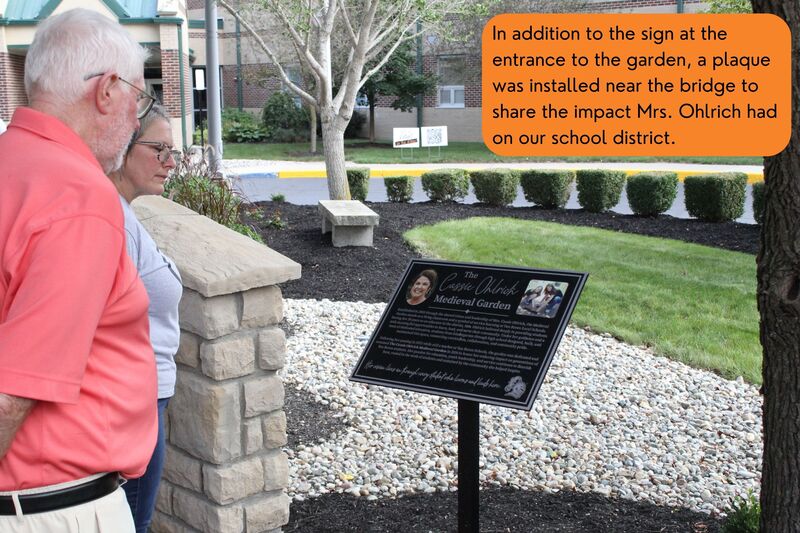 A picture showing the plaque placed to honor Mrs. Ohlrich with attendees reading it.