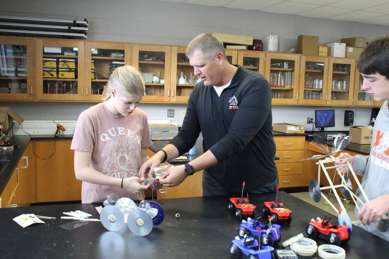 Mr. Adam Schumaker assists a Physics student.