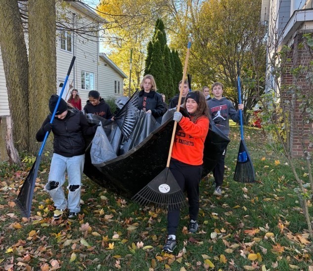 Students carry a tarp full of leaves.