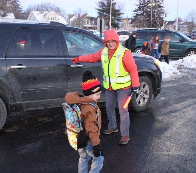 Mrs. Ramlow helps a student out of his car.