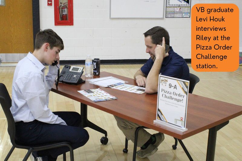 VB graduate Levi Houk interviews Riley at the Pizza Order Challenge station.