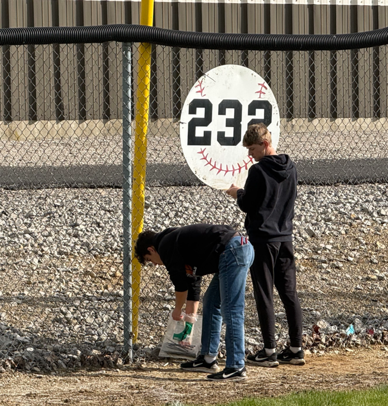 Students help hang the signs on the outfield fence at the Allen Township Sportsplex.