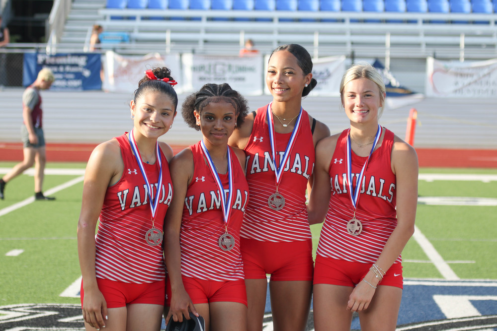 four vandal track girls smile with medals