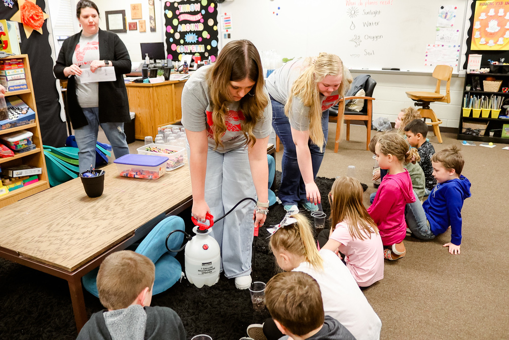 High school FFA students fill up elementary students cups with water and seeds 