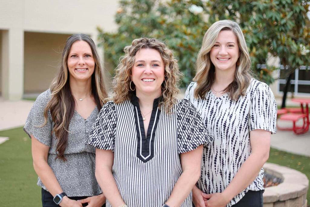 3 women standing in a courtyard. They are the J.E. Rhodes Elementary leadership team