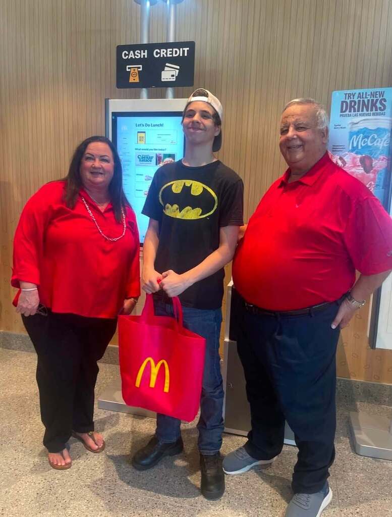 2 adults and 1 young man standing in McDonald's 