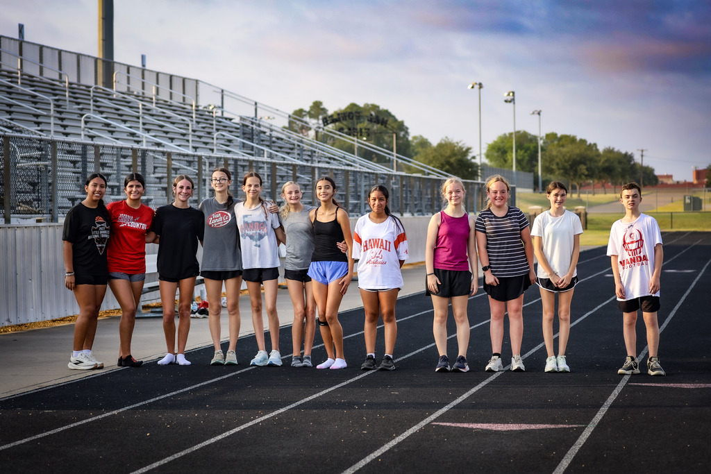 group of people standing on a track smiling