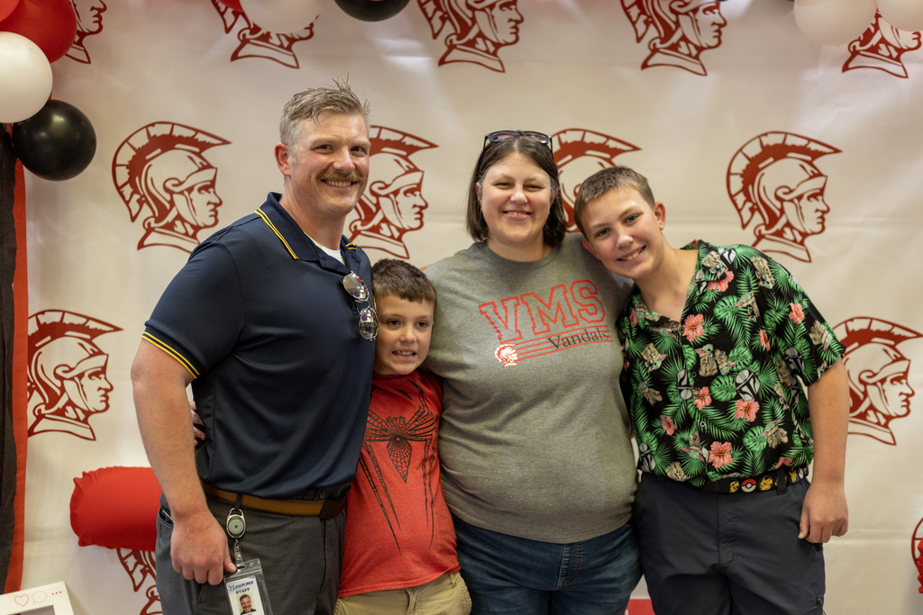Family of four standing together smiling at the camera
