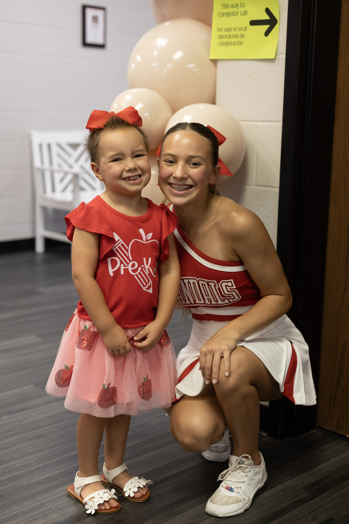 Pre K student and a cheerleader smiling at the camera