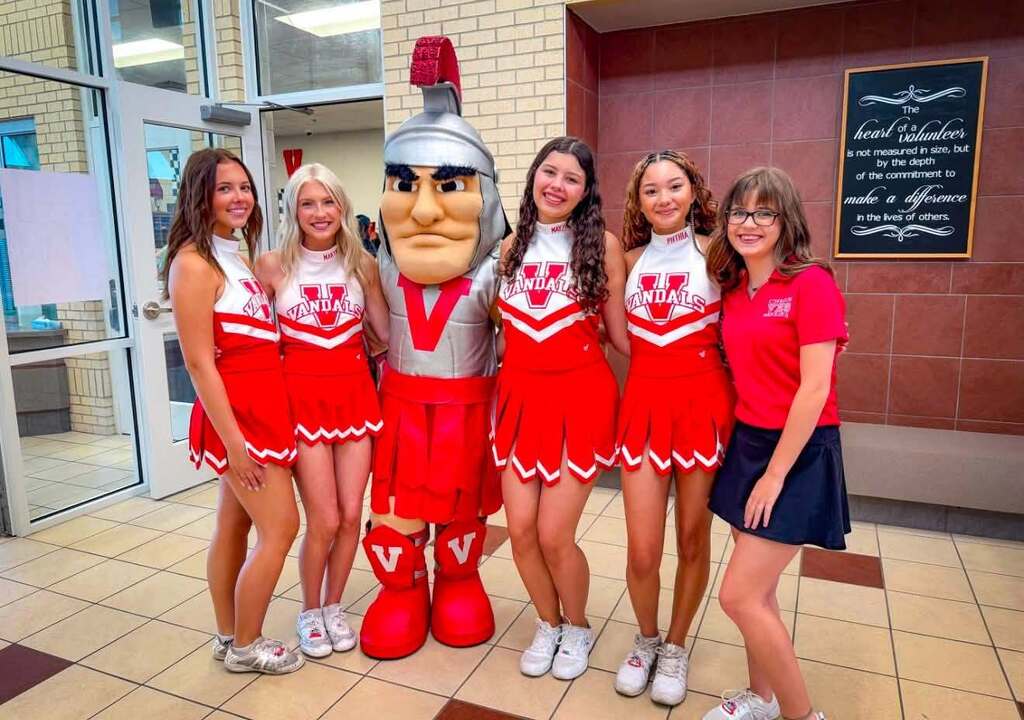 4 cheerleaders, 1 mascot, 1 manager in school hallway