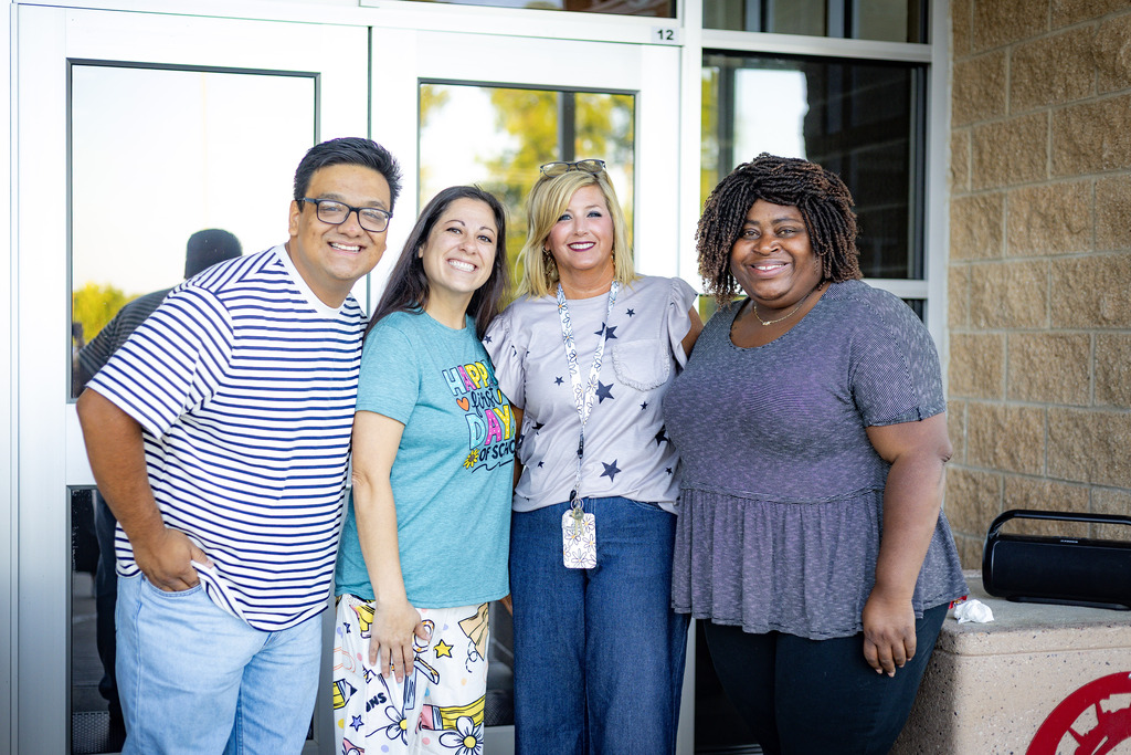 4 adults outside a school building 