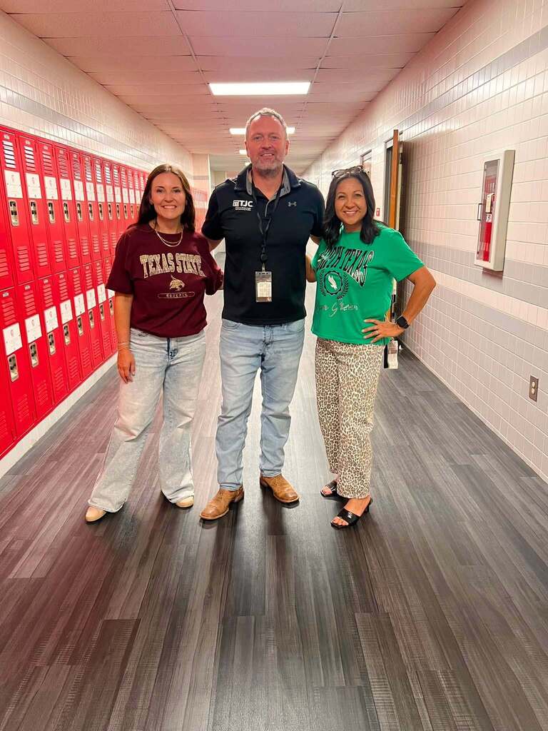 three adults in school hallway