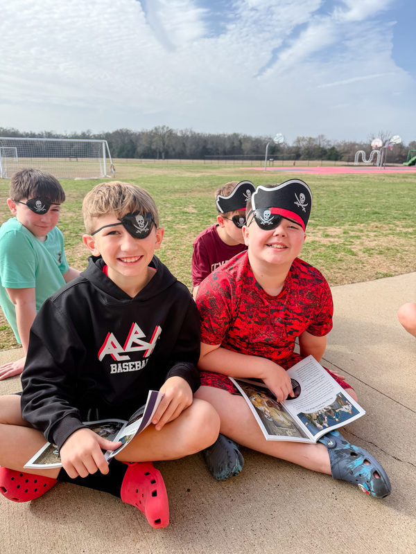 students dressed as pirates reading outside