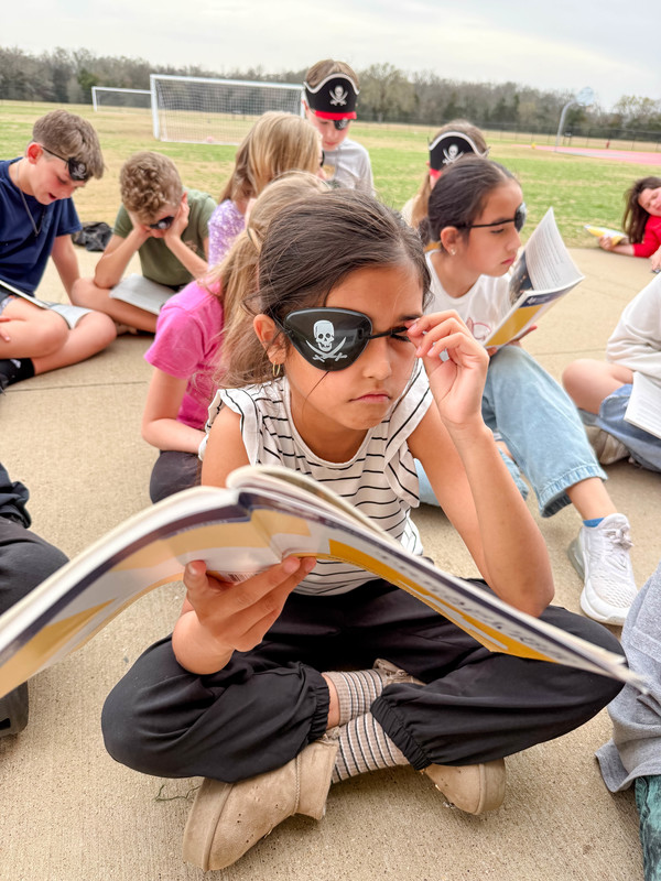 students dressed as pirates reading outside