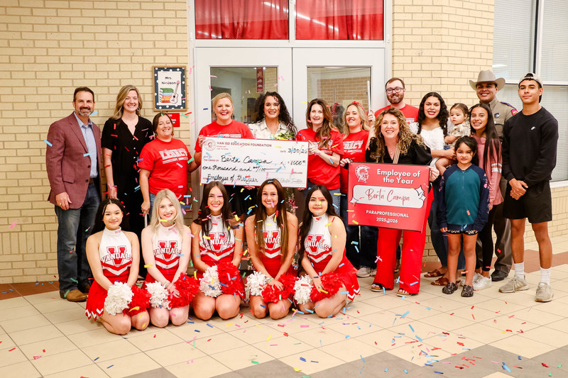 teacher of the year holding a check for $1,000 and cheerleaders and confetti surrounding them