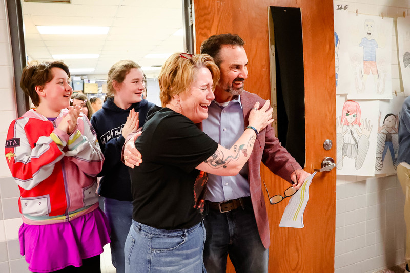 mrs. barker surprised as teacher of the year hugs mr dunn