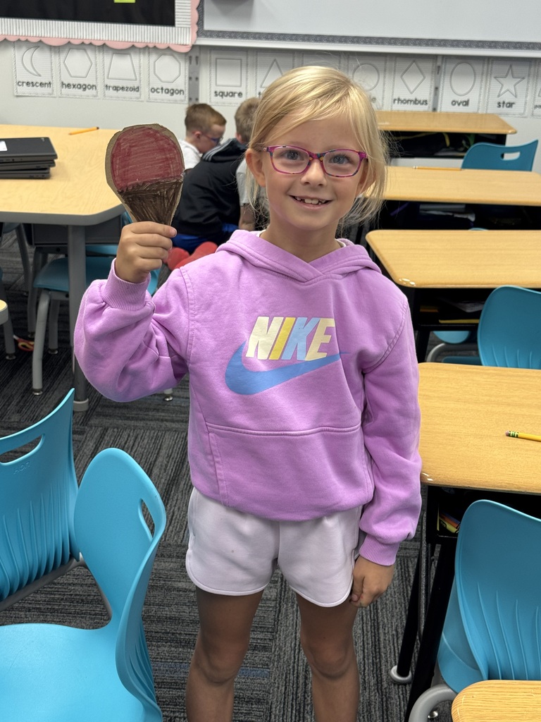 Elementary student smiling and holding up her creation.