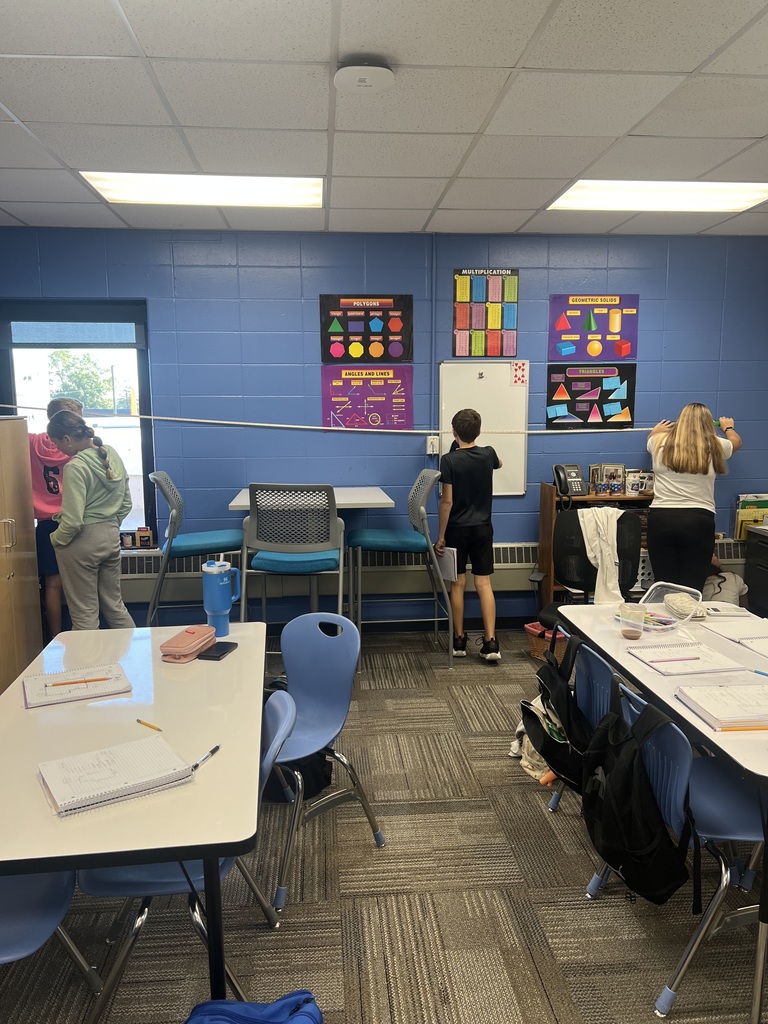 7th grade students measuring a blue wall.
