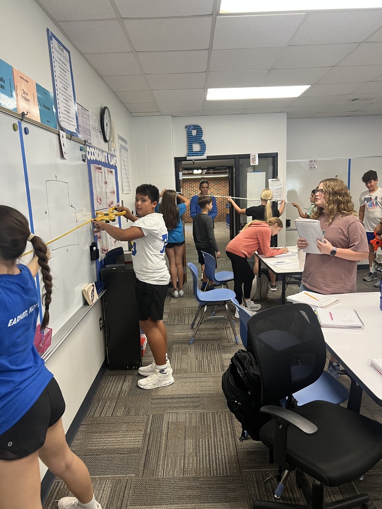 7th grade students measuring on the whiteboard and in the background.
