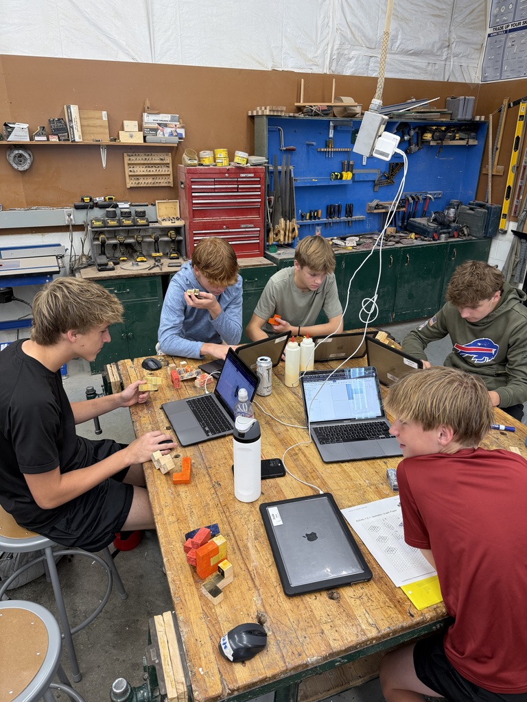 Five students sitting at a table working on their computers.