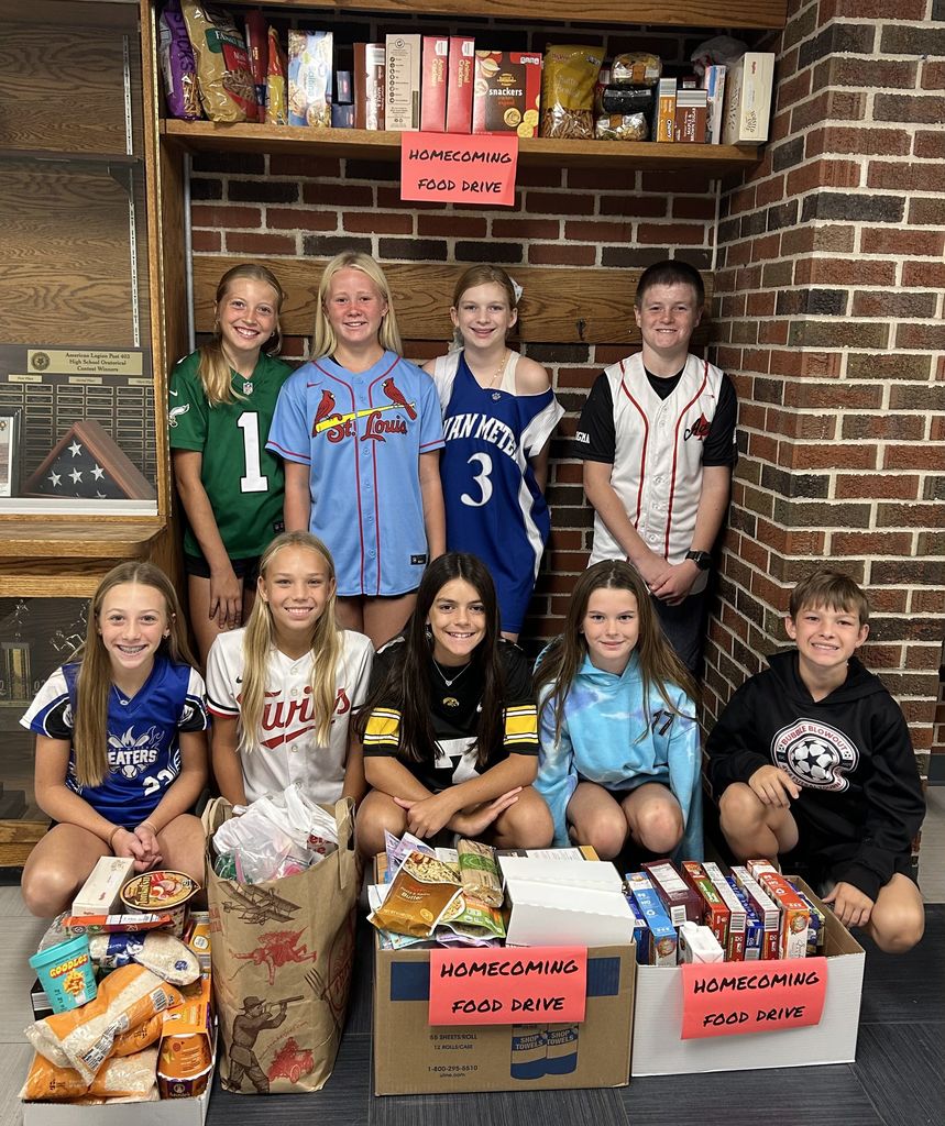 6th graders smiling in front of their food drive collections so far!
