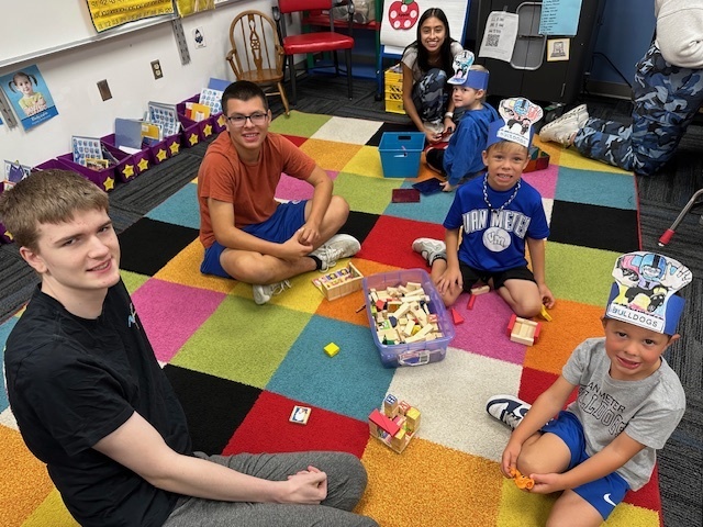 High school buddies working with their elementary partners on a carpet.
