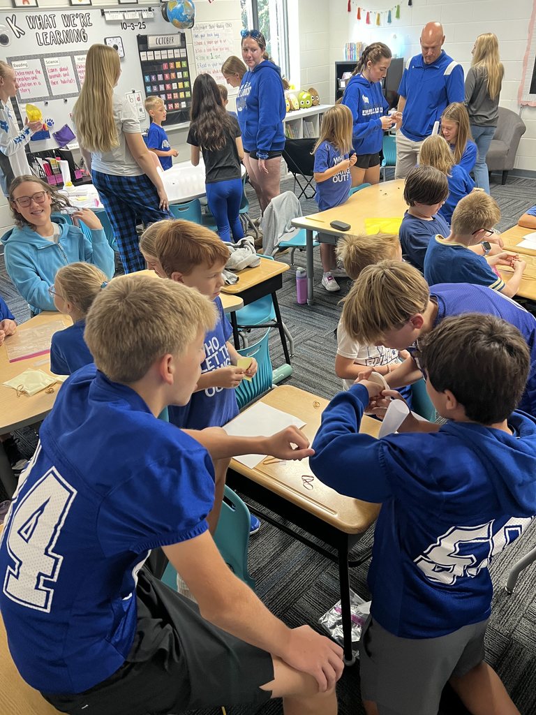 Class buddies working together in small groups at tables.