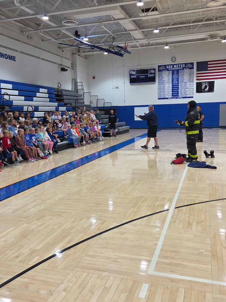 Firemen showing gear to students in the gym.