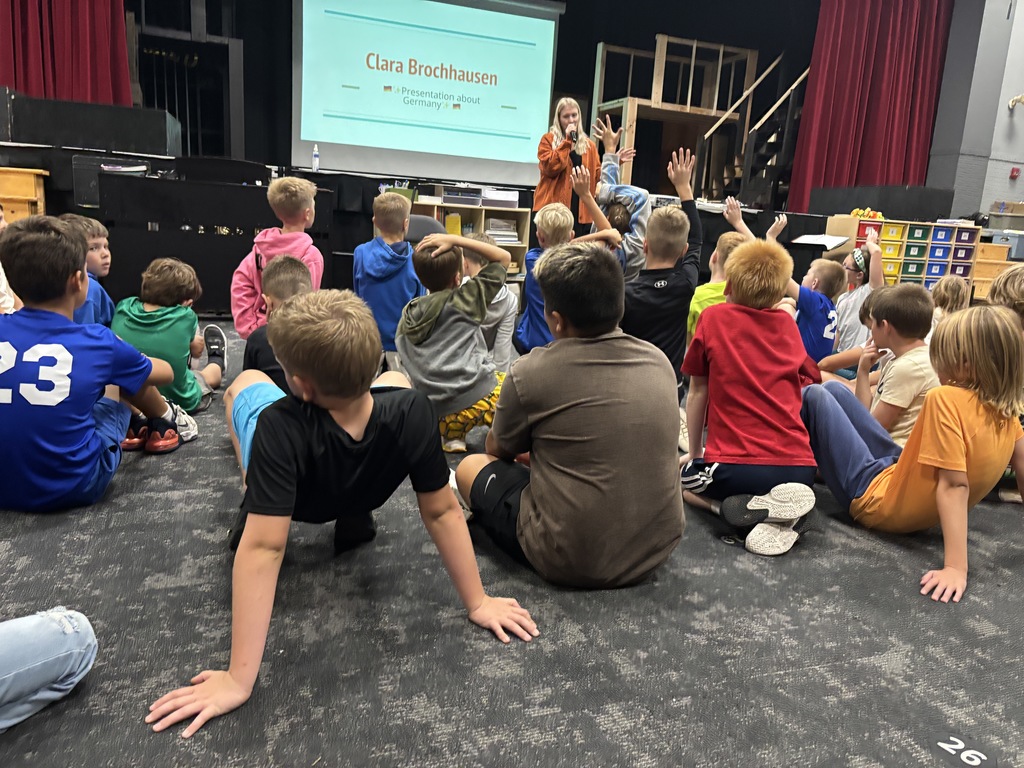 Students listening and raising their hands to ask questions.