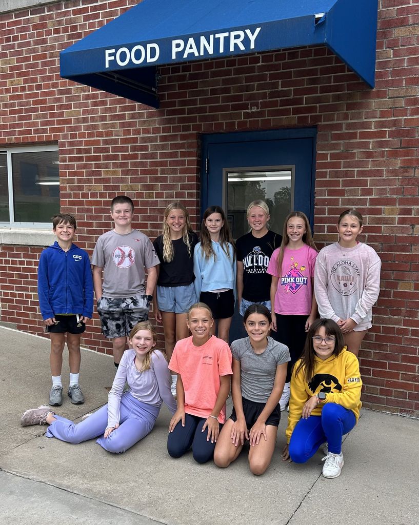 Students smiling in front of the food pantry door.