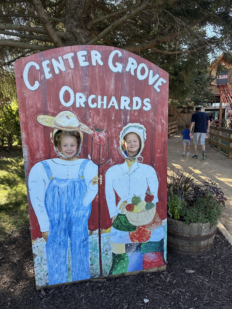 Two students posed behind a cutout for a picture