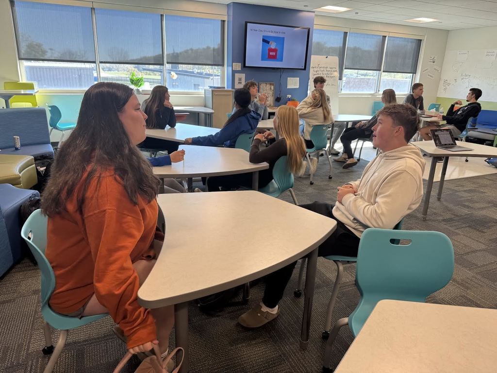 Students debating each other in groups of two for one versus one debate.