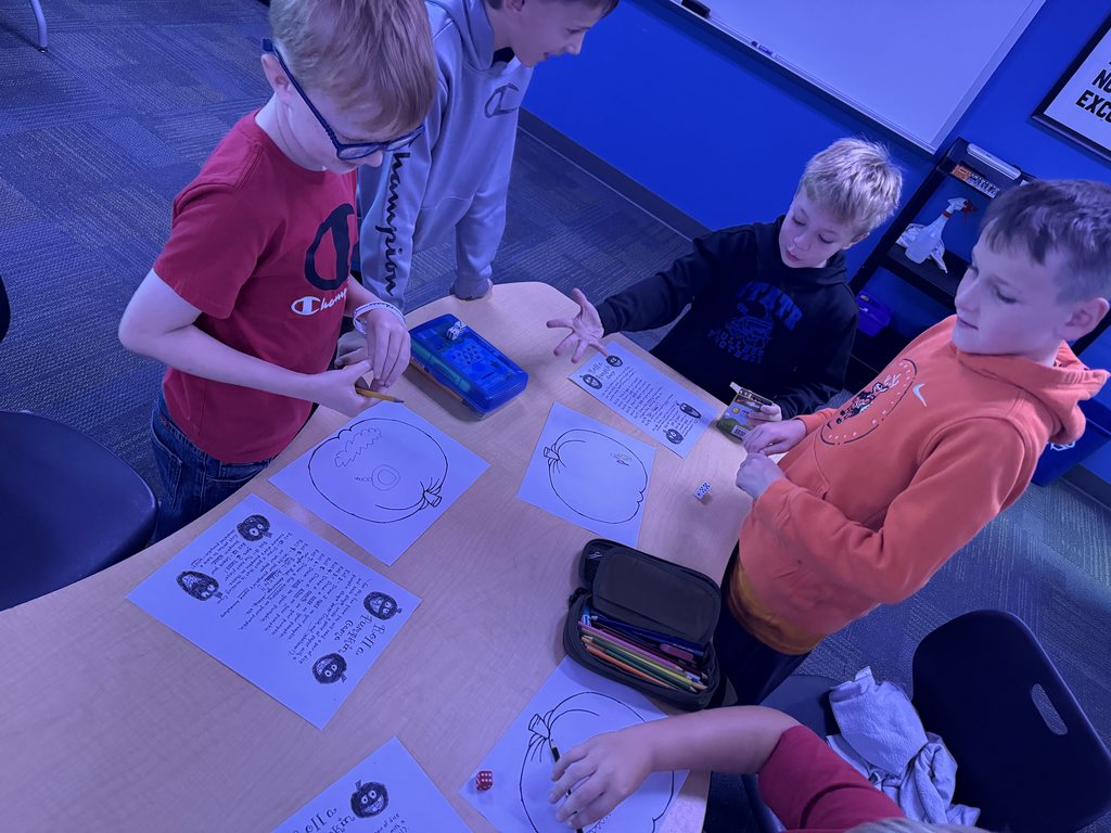 Four students playing the game at the end of a table.