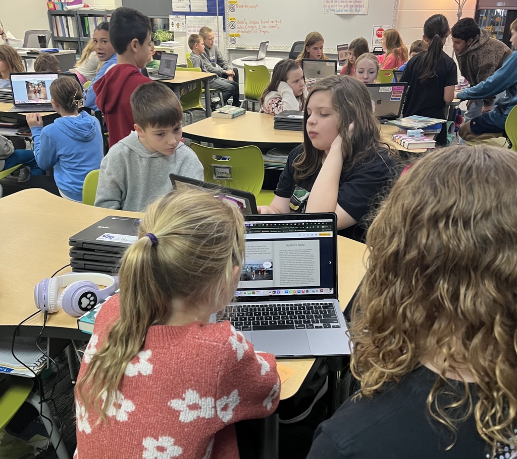 A picture of the room with 7th graders partnered up with 3rd graders and sharing their ebooks.