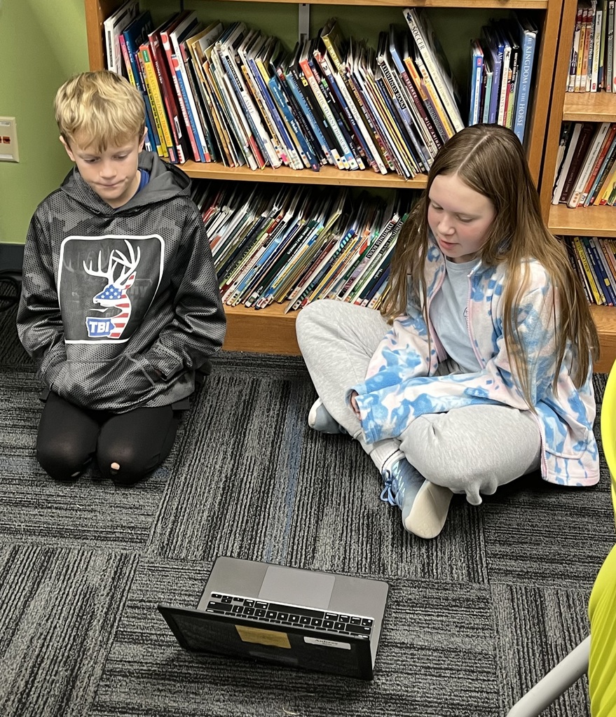 A 7th grader sharing her ebook with a 3rd grader on the floor.
