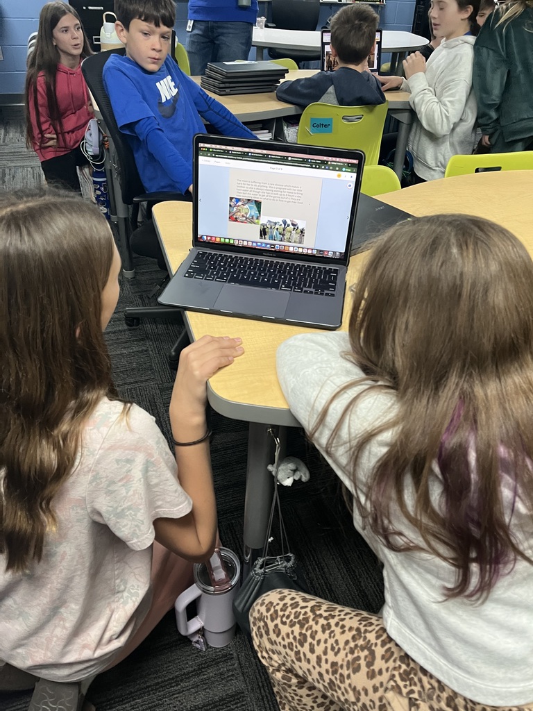 A 7th grader sharing her ebook with a 3rd grader at a desk.