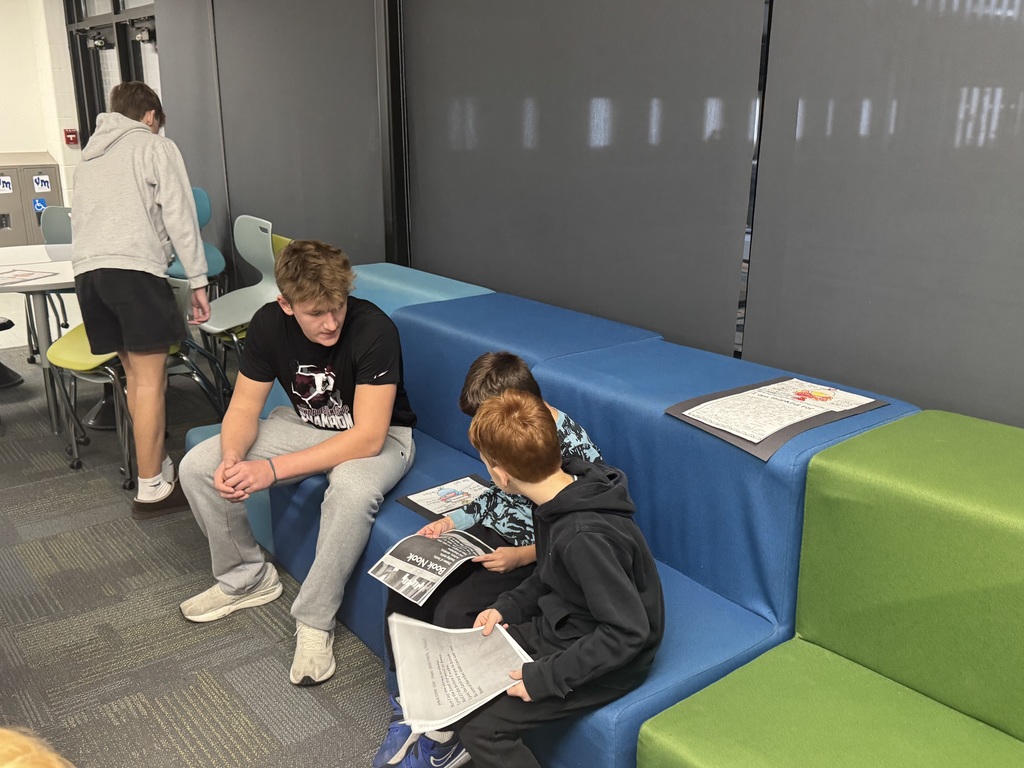 A high school student helping two second graders on a bench.