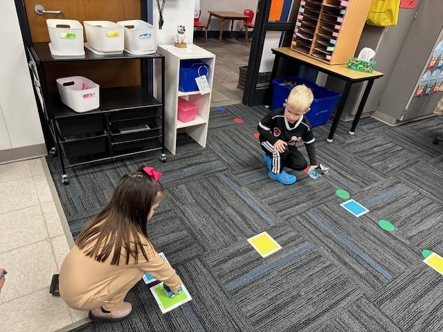 Two students with their card game on the floor.