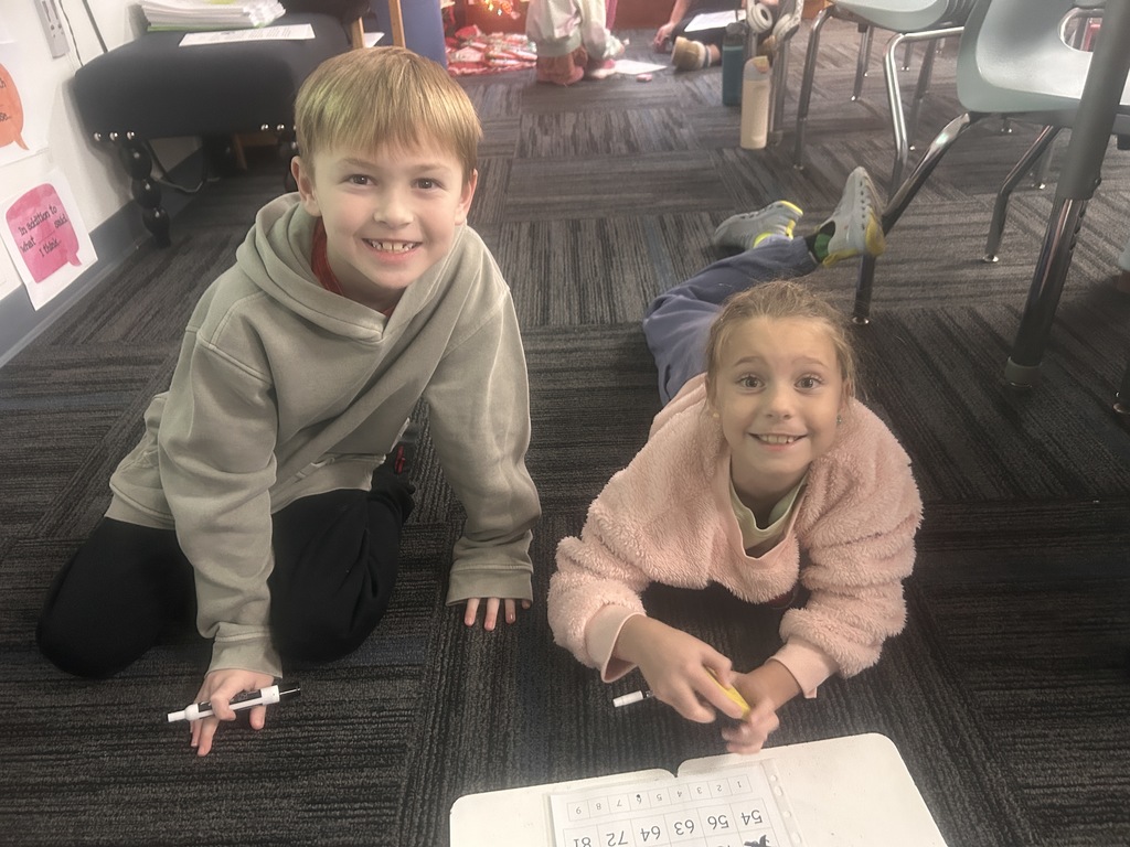 Two students on the classroom floor with their activity in front of them